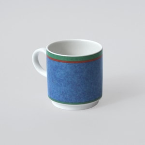 Op de afbeelding: Witte keramische mok met een blauw, getextureerd ontwerp. De mok heeft een groene en rode streep bij de rand. Het handvat is wit en de binnenkant is ook wit. Voor warme of koude dranken.