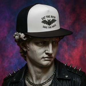 May include: A white and black trucker hat with a black bat graphic and the text "Eat the Rich Save the Bats".