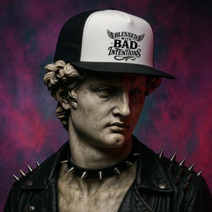 Peut inclure: Une casquette de baseball blanche et noire avec le texte "Blessed with Bad Intentions" en lettres noires. La casquette a une visière noire et une couronne blanche avec un bord noir.