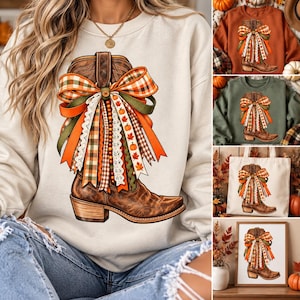 May include: A beige crewneck sweatshirt featuring a graphic of a brown leather cowboy boot adorned with a large, multi-layered bow made of orange, green, and plaid ribbons, accented with dangling wooden beads and small pumpkin and leaf motifs.