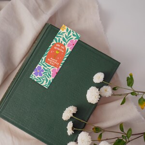 Puede incluir: Un libro verde con un marcap&aacute;ginas que dice "Eres hermosa. Recuerda siempre eso." El marcap&aacute;ginas tiene un dise&ntilde;o floral con flores rosas, amarillas y moradas.