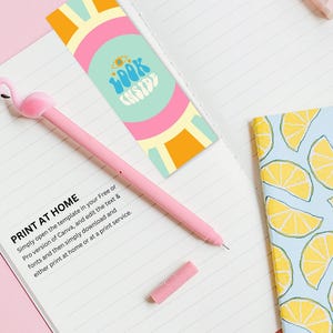 Puede incluir: Un bol&iacute;grafo rosa de flamenco con un cuaderno blanco y un marcap&aacute;ginas colorido que dice "Look Inside".