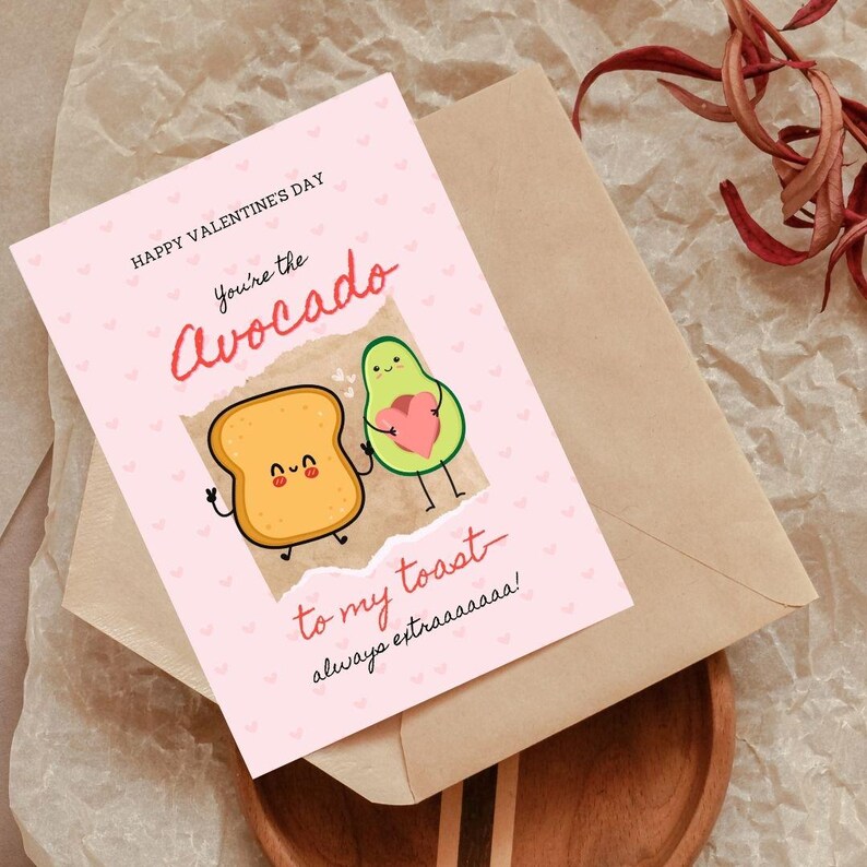 May include: Pink Valentine's Day card with a cartoon avocado and toast. The avocado is holding a heart and the toast has a happy face. The text reads "Happy Valentine's Day You're the Avocado to my toast - always extraaaaa!"