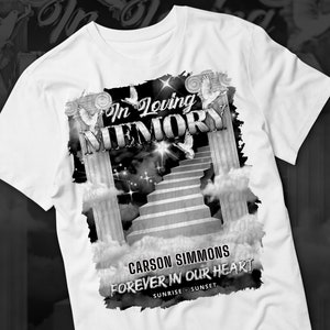 May include: White t-shirt with a black and white graphic design featuring a stairway to heaven, two pillars, doves, and the text "In Loving Memory" and "Carson Simmons Forever In Our Heart Sunrise - Sunset".