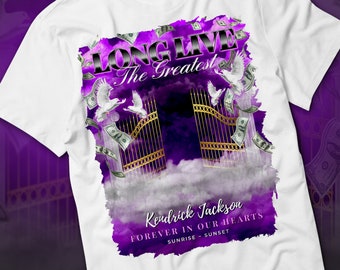 May include: White t-shirt with a purple and gold graphic design featuring a gate, clouds, doves, and dollar bills. The text "LONG LIVE The Greatest" and "Kendrick Jackson FOREVER IN OUR HEARTS SUNRISE - SUNSET" is printed on the shirt.