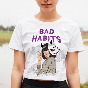 May include: White crop top with a purple graphic of a woman with a fox mask and the text "BAD HABITS".