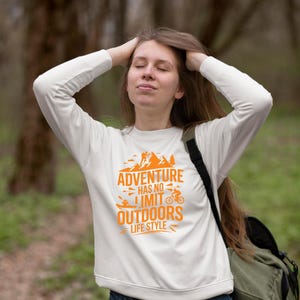A girl wearing white hoodie showcasing adventure themed t-shirt mockup design.