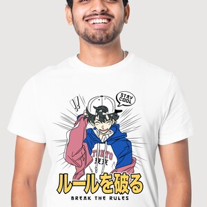 May include: White t-shirt featuring a cartoon illustration of a young man wearing a blue and white hoodie, pink jacket, and a baseball cap. The text "Stay Cool" is in a speech bubble above his head. The text "ルールを破る" and "Break the Rules" are below the illustration.