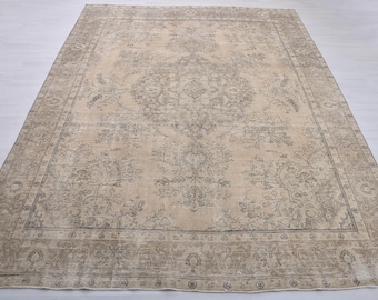 May include: A rectangular area rug featuring a beige background with a faded gray floral and vine pattern. The design includes a central medallion surrounded by intricate botanical motifs and a wide decorative border with repeating geometric shapes.