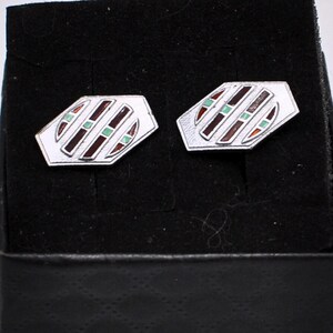 May include: Silver cufflinks with a geometric pattern. Each cufflink features a white base with diagonal stripes in brown, green, and red. The cufflinks are displayed in a black presentation box.