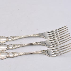 May include: Three silver forks with ornate handles and a polished finish.