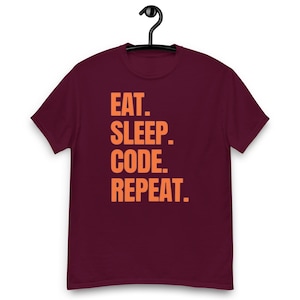 Op de afbeelding: Bordeauxkleurig T-shirt met de tekst "EAT. SLEEP. CODE. REPEAT." in oranje.