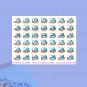 Peut inclure: Une feuille de 36 autocollants représentant une tortue de dessin animé prenant un bain dans une baignoire bleue avec un robinet. Les autocollants sont blancs avec un contour rose et le texte "CHARM'N DREAMS", "CHARMDREAMS.COM" et "@CHARM.N.DREAMS" en bas.