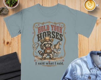Maglietta da cowboy con procione e scritta divertente "Hold Your Horses" (Tieni i cavalli) con grafica di animali western, citazione sarcastica, stile country, regalo