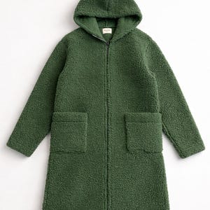 May include: A forest green long-sleeve coat made of textured sherpa fleece material. This hooded coat features a full-length front zipper closure, two large square patch pockets on the front, and a straight hemline that reaches mid-thigh length.