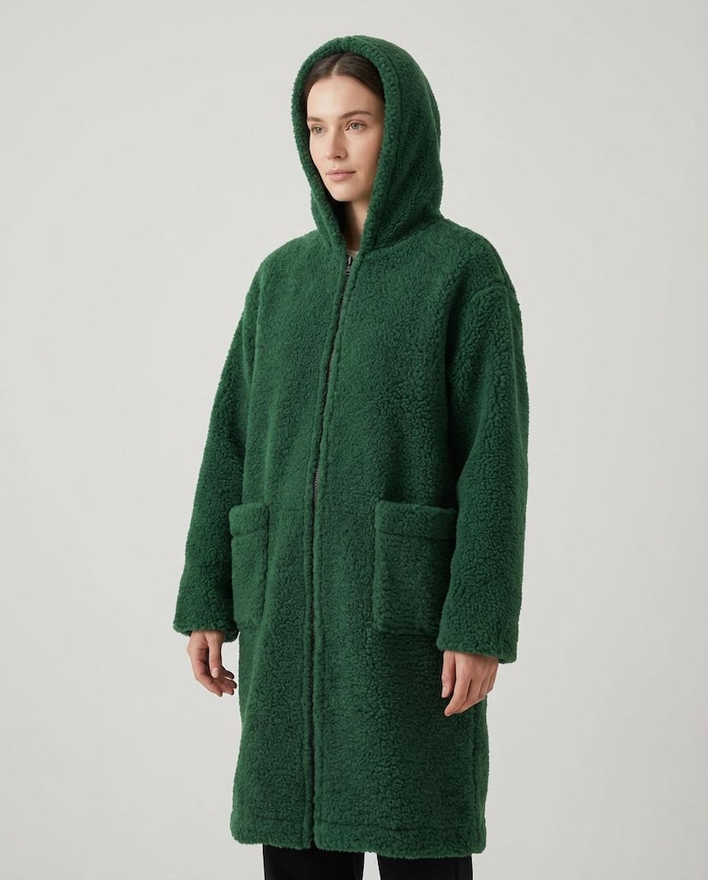 May include: A forest green zip-up coat made of a textured, curly fleece material. This long-sleeved garment features a hood, a full-length front zipper closure, and two large, square patch pockets positioned on the front of the coat.