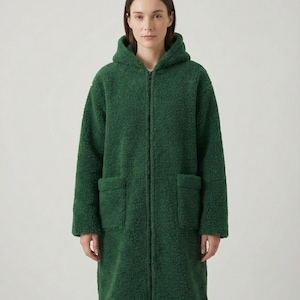 May include: A long-length, forest green hooded coat made of a textured, fuzzy fleece material. The coat features a full-length front zipper closure, long sleeves, and two large, rectangular patch pockets positioned on the front of the garment.