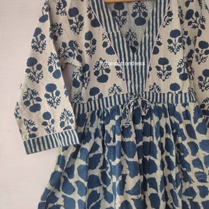 May include: A blue and white cotton dress with a V-neckline and a tie at the waist. The dress has a floral print and a striped pattern.