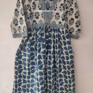 May include: A blue and white cotton dress with a floral print and a V-neckline. The dress has a tie at the waist and three-quarter sleeves.