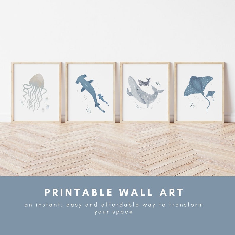 May include: Set of four printable wall art prints featuring watercolor illustrations of ocean animals. The prints depict a jellyfish, a hammerhead shark, a whale, and a stingray. The prints are framed in natural wood frames and are ready to hang.