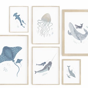 May include: Set of six framed watercolor illustrations of various sea creatures, including a hammerhead shark, a jellyfish, a whale, a stingray, a narwhal, and a dolphin. Each illustration is framed in a light wood frame and features a white background with blue and gray watercolor details.