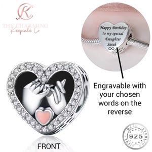 Könnte beinhalten: Ein silberner herzförmiger Charm-Anhänger mit einem rosa Herz und zwei ineinander verschlungenen Händen. Der Charm ist von klaren Kristallen umgeben. Der Text "Happy Birthday to my special Daughter Sarah" ist auf einem herzförmigen Charm eingraviert. Der Text "Engravable with your chosen words on the reverse" ist ebenfalls sichtbar.