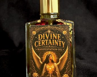 May include: A clear glass bottle filled with golden oil and dried botanicals, topped with a gold dropper cap. The rectangular label features the text "DIVINE CERTAINTY MANIFESTATION OIL WITCH ELIXIR" and an illustration of a winged figure with a halo.