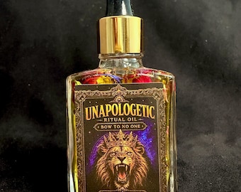 May include: A clear glass bottle filled with yellow liquid and dried flower petals, topped with a gold and black dropper cap. The label features a lion wearing a crown, a purple galaxy background, and the text UNAPOLOGETIC RITUAL OIL BOW TO NO ONE.