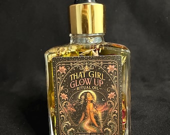 May include: A clear glass bottle filled with yellow oil and dried flower petals, topped with a gold dropper cap. The rectangular label features the text THAT GIRL GLOW UP RITUAL OIL and an illustration of a figure sitting by the water at sunset.