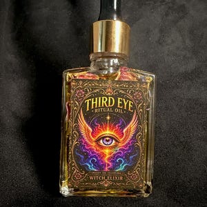 Puede incluir: Un frasco de vidrio rectangular con tapa de gotero dorada que contiene un líquido amarillo y pétalos de flores secas. La etiqueta presenta un gráfico colorido de un ojo alado con el texto "THIRD EYE RITUAL OIL" y "AWAKEN SEE TRANSFORM WITCH ELIXIR".