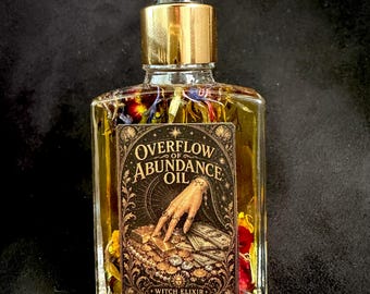 Op de afbeelding: Een doorzichtige glazen fles met een gouden druppeldop, gevuld met gele olie en gedroogde bloemblaadjes. Het rechthoekige etiket toont een illustratie van een hand die goudstaven en munten aanraakt met de tekst OVERFLOW OF ABUNDANCE OIL WITCH ELIXIR.