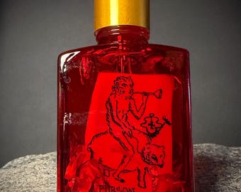 Op de afbeelding: Een rode glazen fles met een gouden dop en witte druppelaar. De fles heeft een rood etiket met een zwarte illustratie van een figuur die op een dier rijdt en het woord "PURSON".