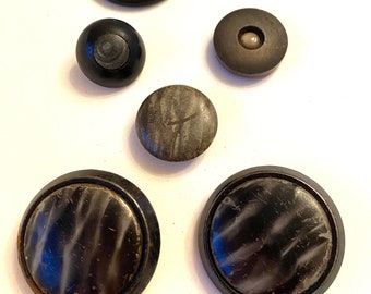 A collection of 11 black and grey, vintage and antique buttons, large coat buttons and others.