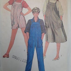 May include: A Simplicity 5512 sewing pattern envelope for maternity clothing in size medium 14-16. The illustration shows three variations of overalls: a red and white striped short version, a solid blue long version, and a solid gray dress version.