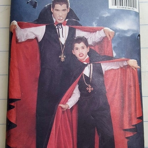 May include: A vintage Butterick pattern envelope featuring a vampire costume design. The image shows a man and a child dressed in black vests, pants, and capes with red linings. The costumes include white shirts, bow ties, and cross pendants. The envelope has the number 4971.