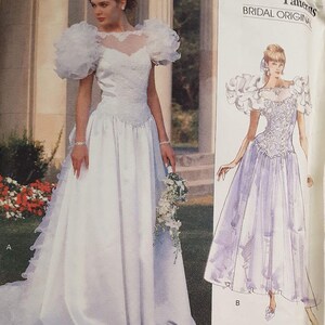 May include: A vintage Vogue Patterns bridal dress pattern, featuring a white gown with a ruffled skirt and puffed sleeves. The pattern is labeled "Advanced/Plus Difficulty" and "Pattern/Patron 2396".