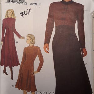 May include: A vintage Butterick sewing pattern featuring illustrations of women's dresses. The pattern includes a long-sleeved dress with a high neckline and a flared skirt, and a shorter dress with a similar design. The pattern size is 18-20-22.