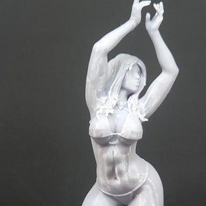 May include: A gray 3D printed figurine of a person in a swimsuit pose with arms raised above their head.
