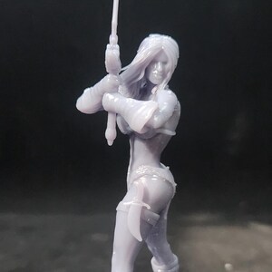 May include: A gray 3D printed figurine of a female warrior holding a sword. The figurine is standing on a round base.