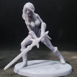 May include: A gray 3D printed figurine of a female warrior holding a sword in a fighting pose. The figurine is standing on a round base.