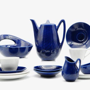 May include: A collection of cobalt blue and white ceramic tableware. The set includes a teapot, cups, saucers, bowls, and a creamer. The blue pieces have a textured pattern. The white cups and saucers provide a contrast.