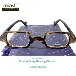 May include: Reading glasses with a matte finish, featuring a tortoise shell pattern on the frames and black arms. The glasses have a rectangular shape and are labeled "Small & Funky Reading Glasses" and "Optical Quality."