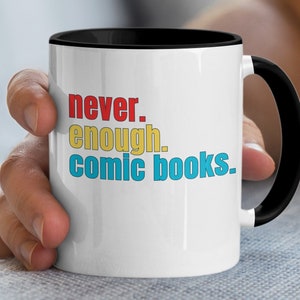 May include: White ceramic mug with a black rim and handle. The mug has the text "never. enough. comic books." printed on it in colorful letters.