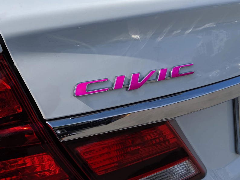 May include: A white car with a pink "CIVIC" emblem on the back.