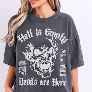 May include: Dark gray t-shirt with the text "Hell is Empty and All the Devils are Here" and a white skull graphic. The shirt has a vintage, worn look.