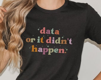 May include: Black t-shirt with the text "data or it didn't happen" in colorful, retro-style lettering. The shirt has a crew neck and short sleeves. The design includes stars around the text.