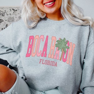 May include: A gray sweatshirt with a pink and orange graphic print that says "Boca Raton, Florida" with a palm tree.
