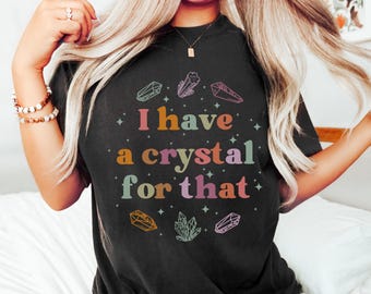 May include: Black t-shirt featuring the text "I have a crystal for that" in various colours, with crystal and star illustrations. The tee is a relaxed fit, suitable for everyday wear.
