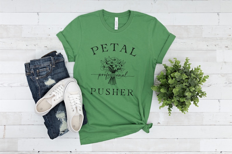 May include: Green t-shirt with a black graphic of a bouquet of flowers and the text "PETAL professional PUSHER".