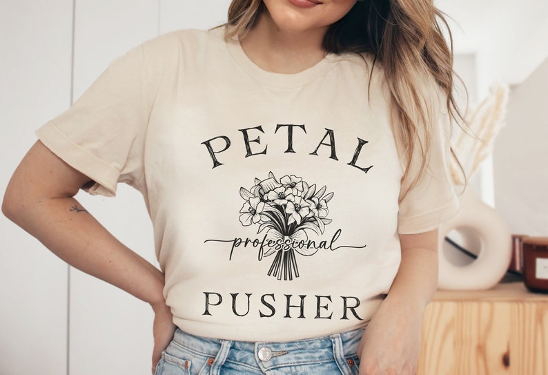 May include: A cream colored t-shirt with black text that reads "PETAL professional PUSHER" and a black and white illustration of a bouquet of flowers.